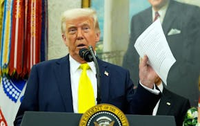 FILE - President Donald Trump holds a document with notes about Kilmar Abrego Garcia as he speaks with reporters in the Oval Office of the White House