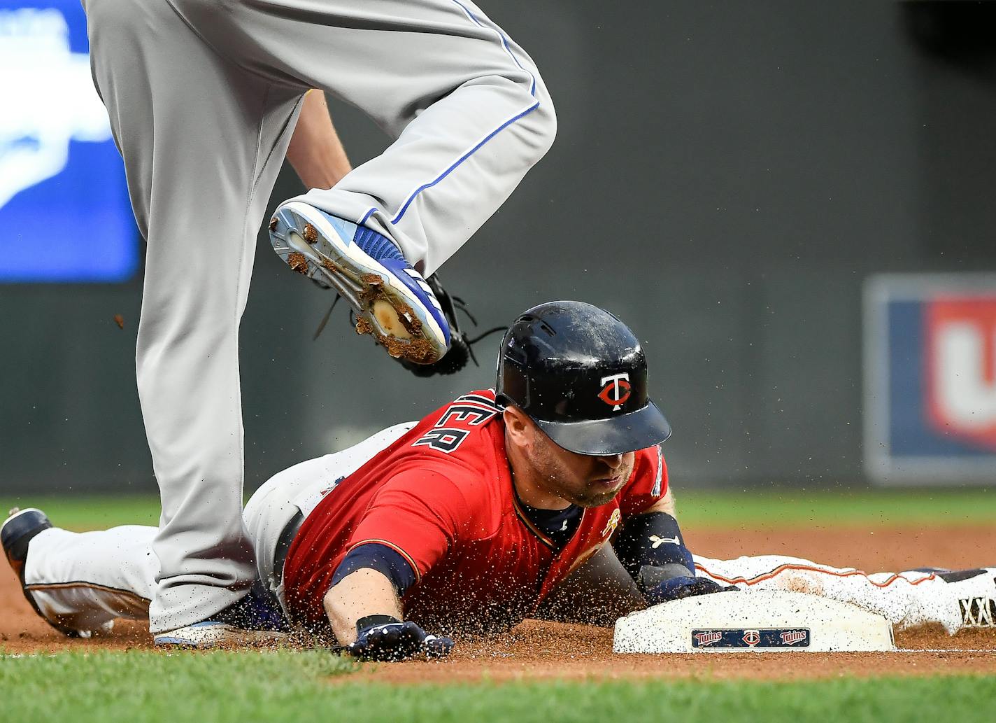 After tagging back to second base following a fly out by Twins first baseman Joe Mauer to center field, second baseman Brian Dozier slid safely into third base in the bottom of the first inning.