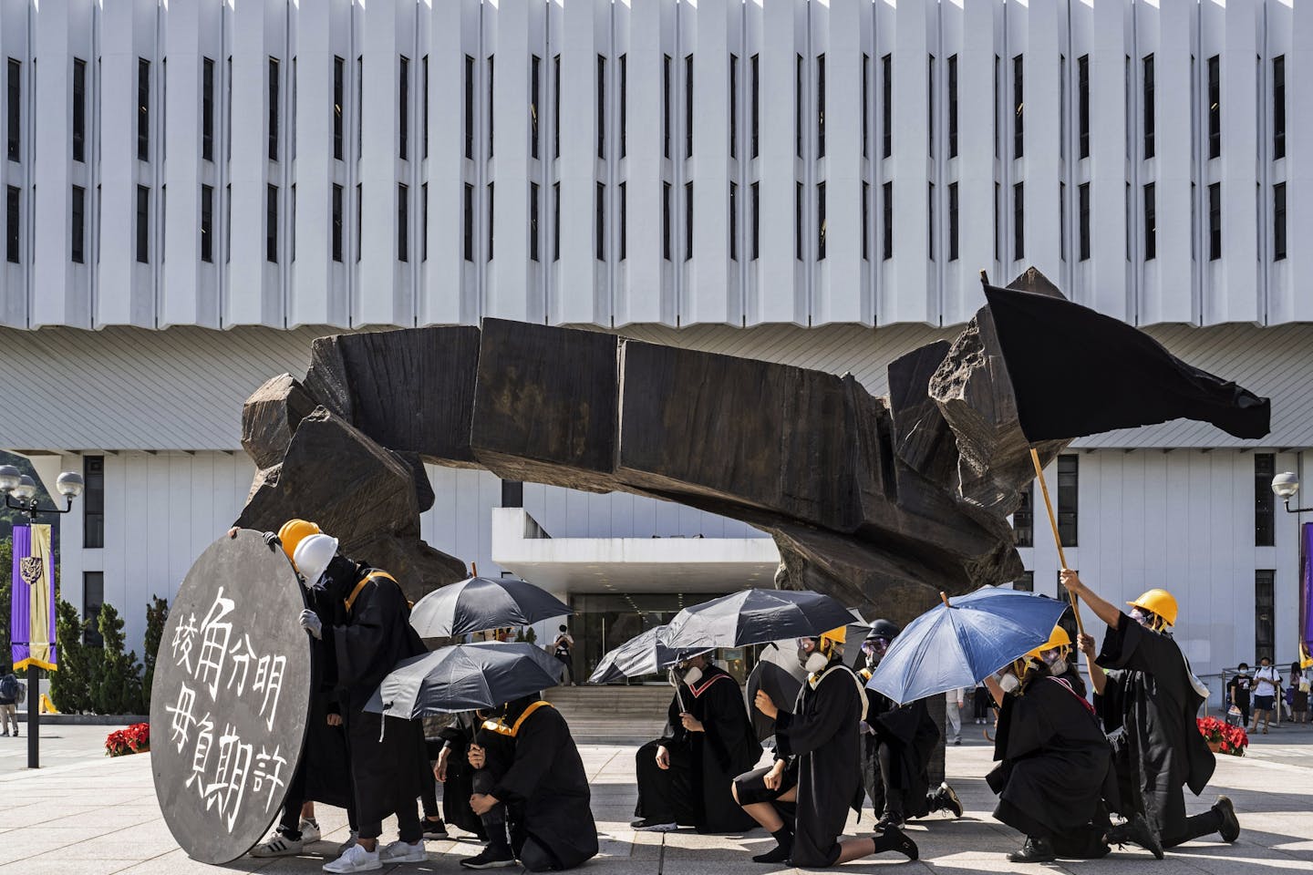 University students wearing black graduation gowns, helmets and protective masks stage a protest at the Chinese University of Hong Kong campus on Nov. 19, 2020. Hong Kong authorities on Monday, Dec. 7, 2020, arrested eight people in connection with an unauthorized protest at a university campus last month, police and local media said, amid a widening crackdown on dissent in the semi-autonomous Chinese territory.