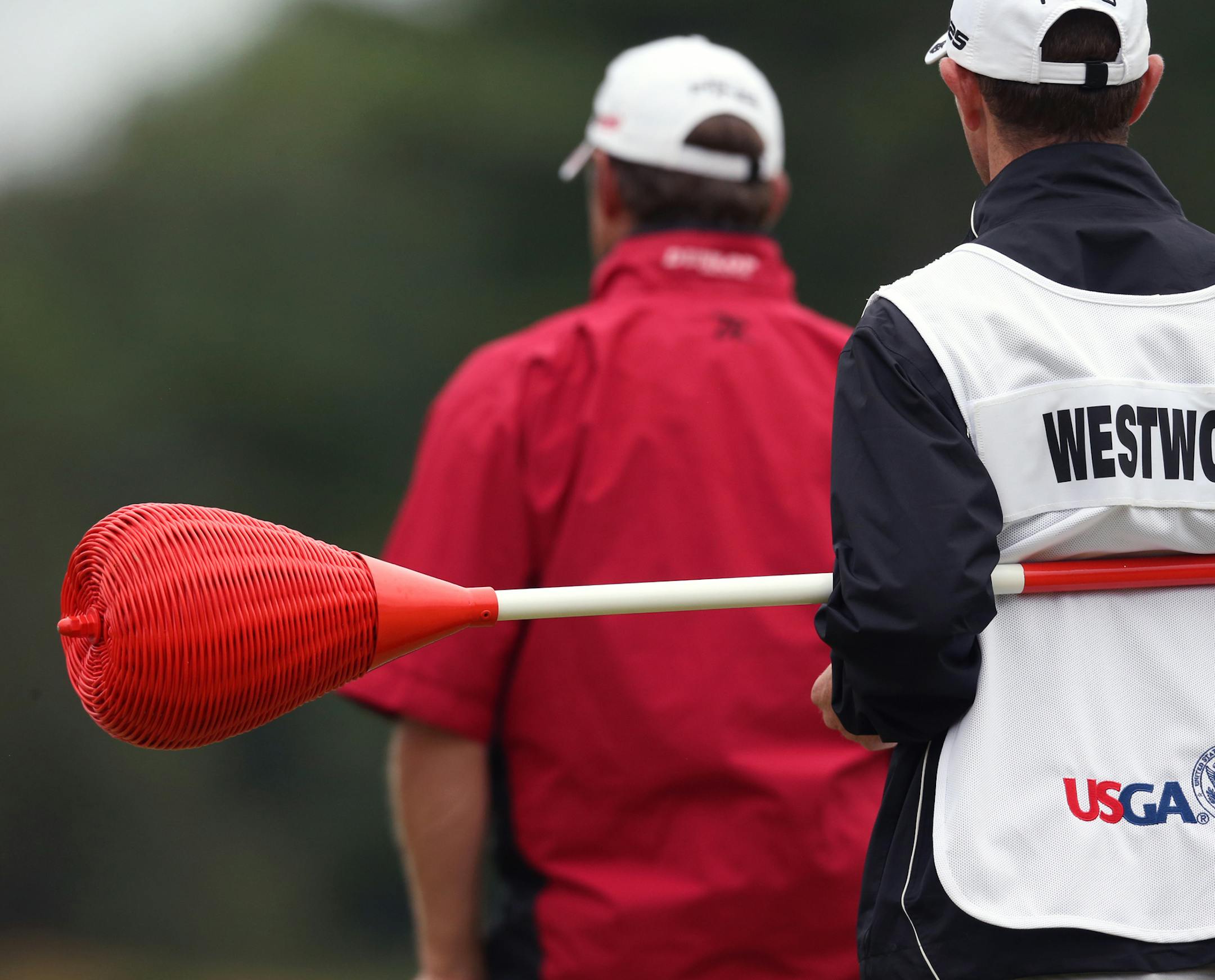 Lee Westwood's caddie holds the one of the unique Merion pins topped with wicker baskets in place of the usual flags during the first round of the US Open at the Merion Golf Club in Ardmore, Pa., June 14, 2013. The rain-delayed first round will end at the golf club Friday, with the last of the 78 players who did not finish the first round on Thursday currently finishing up while the second round has begun. (Doug Mills/The New York Times)