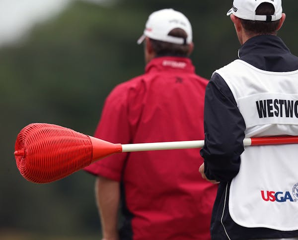 Lee Westwood's caddie holds the one of the unique Merion pins topped with wicker baskets in place of the usual flags during the first round of the US 
