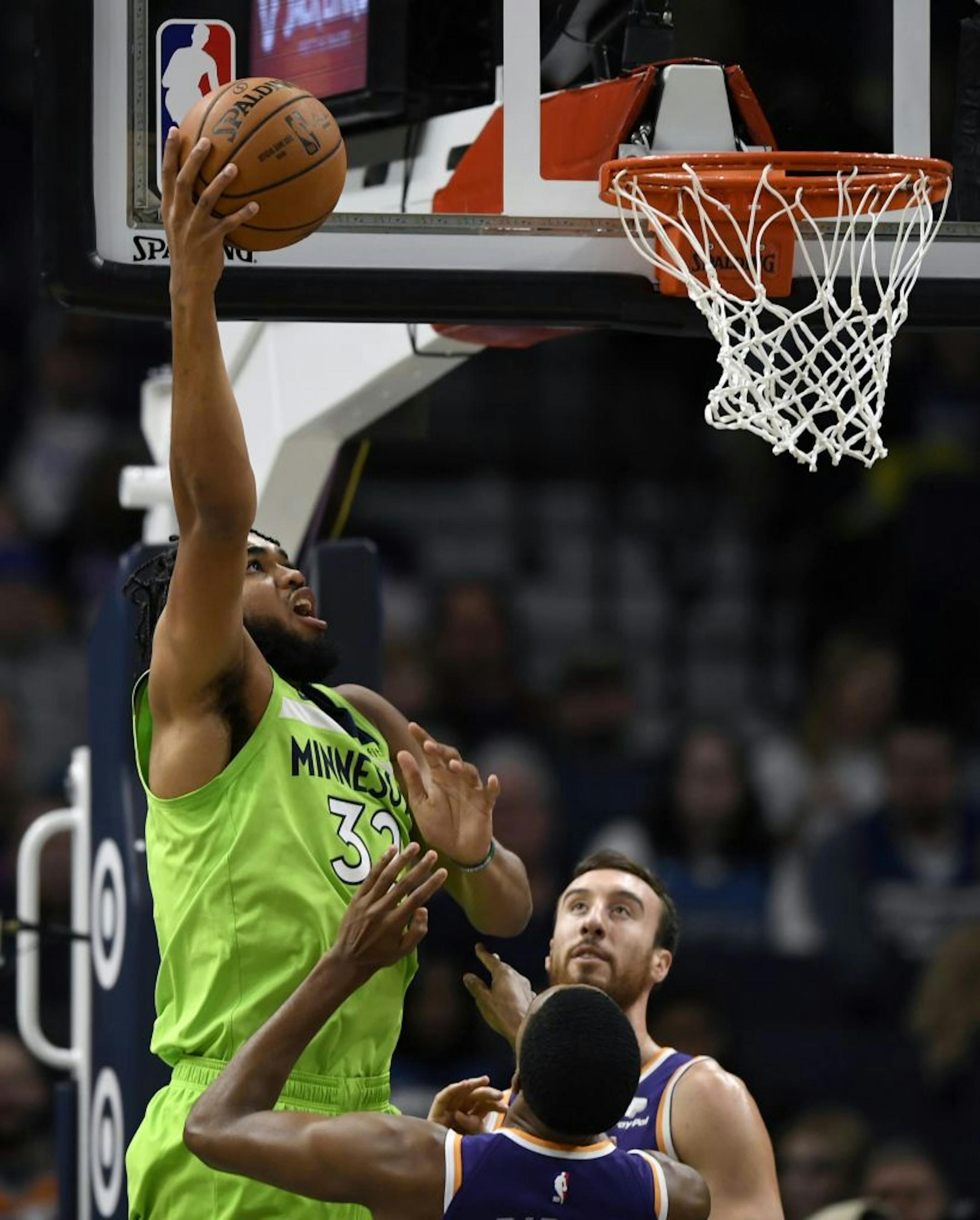Minnesota Timberwolves' Karl-Anthony Towns (32) shoots a layup over Phoenix Suns' Mikal Bridges, center, and Frank Kaminsky during the first quarter of an NBA basketball game on Saturday, Nov. 23, 2019, in Minneapolis.