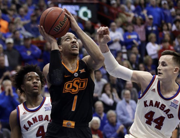 Oklahoma State guard Kendall Smith (1) shoots after getting past Kansas defenders Devonte' Graham (4) and Mitch Lightfoot (44) during the second half 
