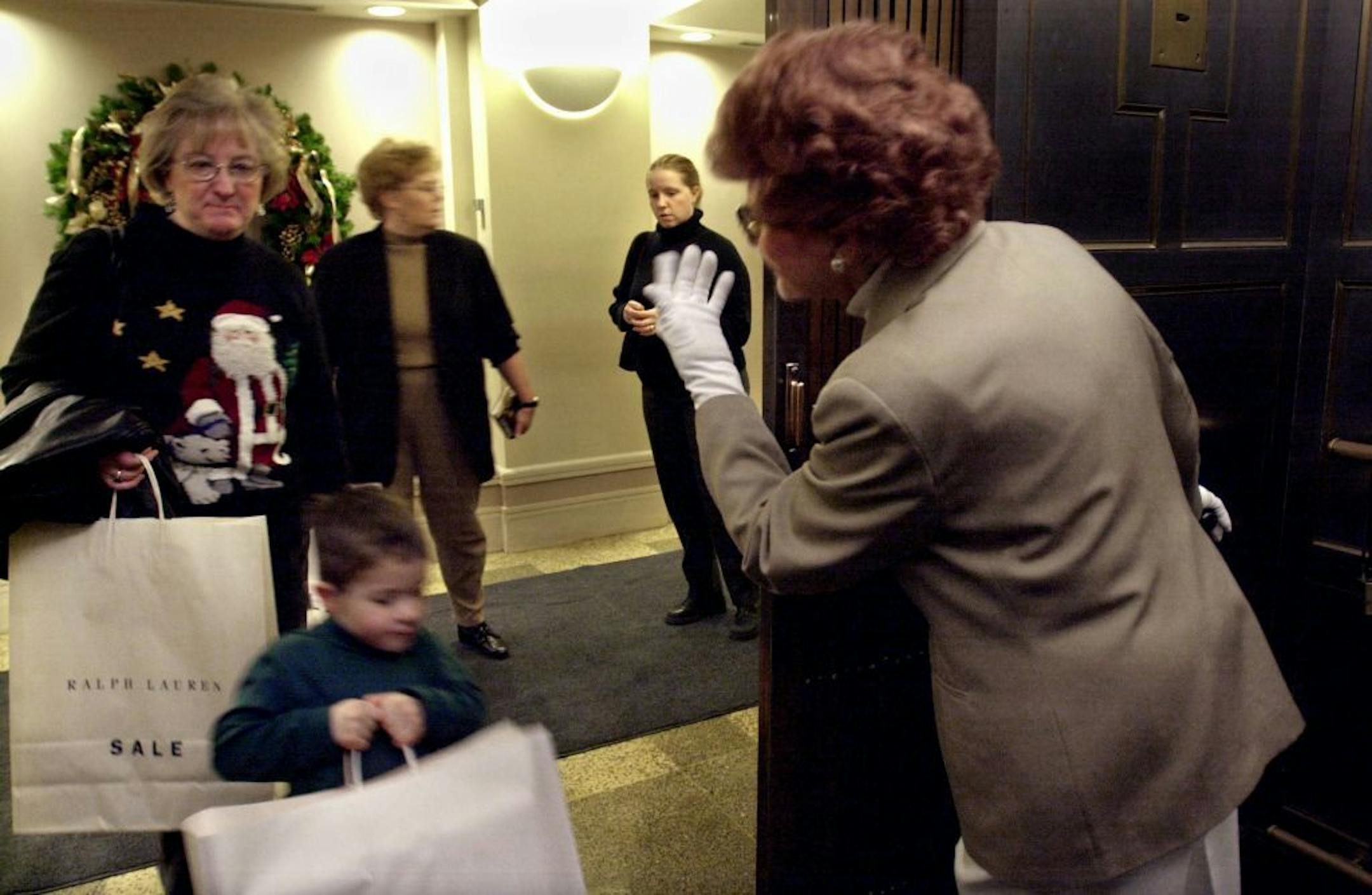 Minneapolis, Mn., Thurs., Jan. 3, 2002--Elevator operator Millie DeZiel motions riders on offering to go up or down to suit them. DeZiel works in the Young Quinlan Building where one elevator will remain with white-gloved elevator operators. One elevator was converted to self-serve in 1985 and another will be converted later this month.