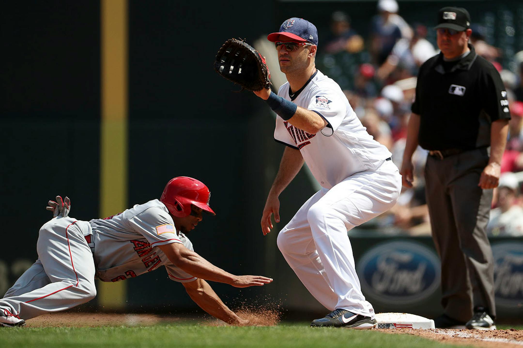 Minnesota Twins first baseman Joe Mauer (7) checks Los Angeles Angels left fielder Ben Revere (25) at first in the fifth inning.