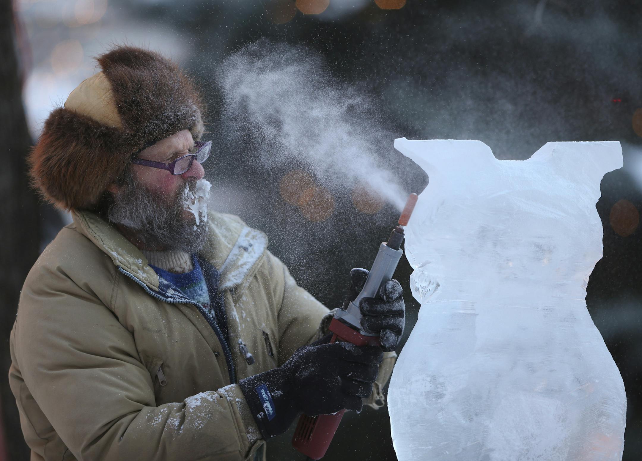 The Coolest Celebration on Earth lived up to its name when the 128th St. Paul Winter Carnival kicked off Thursday night, January 23, 2014 with the Moon Glow Parade that ended in Rice Park in downtown St. Paul. John Raak of St. Paul removed ice with a sanding drum from the owl he was carving in the multi-block competition that began on Thursday. He and three other carvers have until Saturday at noon to finish a creation they're calling "Icechanted Garden." "It's a marathon," he said. "We won't be