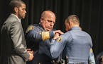 With St. Paul Mayor Melvin Carter to the left, St. Paul Police Chief Todd Axtell pins orVictor Rodriquez, 25, as newly minted officer. He overcame ser