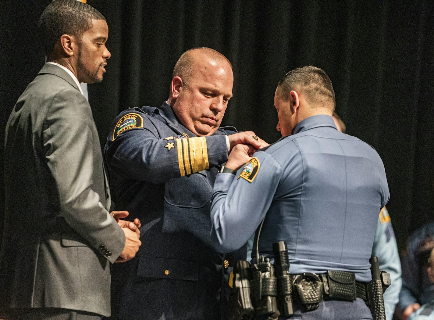 With St. Paul Mayor Melvin Carter to the left, St. Paul Police Chief Todd Axtell pins orVictor Rodriquez, 25, as newly minted officer. He overcame serious socioeconomic obstacles and a troubled youth to join St. Paul's Law Enforcement Career Path Academy, becomes the first in his family to earn a higher ed degree.] St. Paul police will graduate its most diverse recruiting class ever Thursday night at Harding H.S. The class of 39 SPPD recruits is 77% people of color.RICHARD TSONG-TAATARII ¥ richa