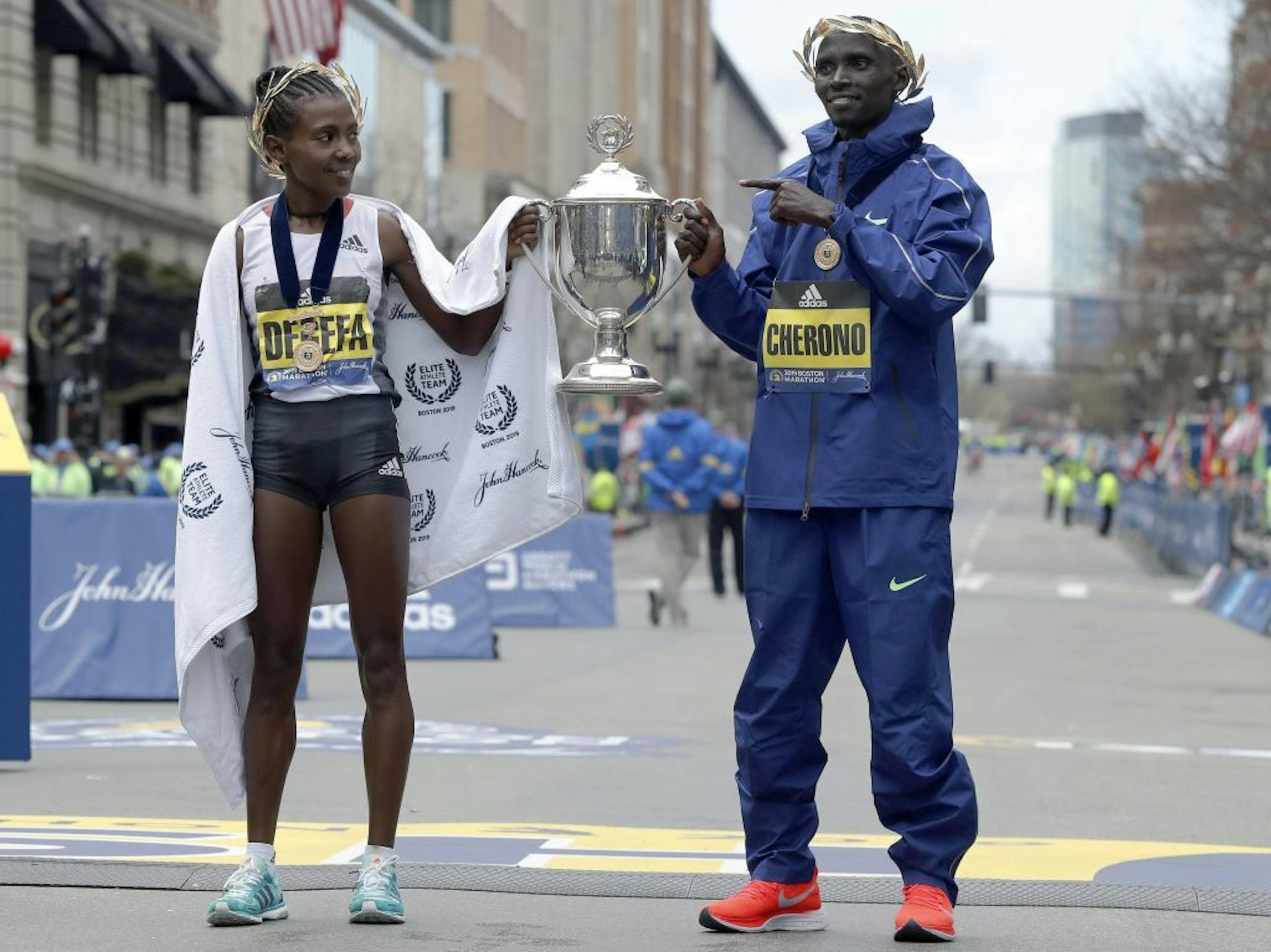 Worknesh Degefa, left, of Ethiopia, winner of the women's division, and Lawrence Cherono, right, of Kenya, winner of the men's division of the 123rd Boston Marathon, hold the trophy at the finish line on Monday, April 15, 2019, in Boston.