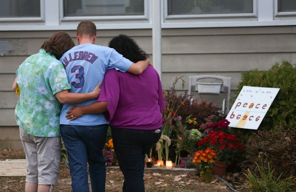A family members of Ron Edberg consoled his son Dusty, center, in front of an informal memorial made for the victims in front of Accent Signage System
