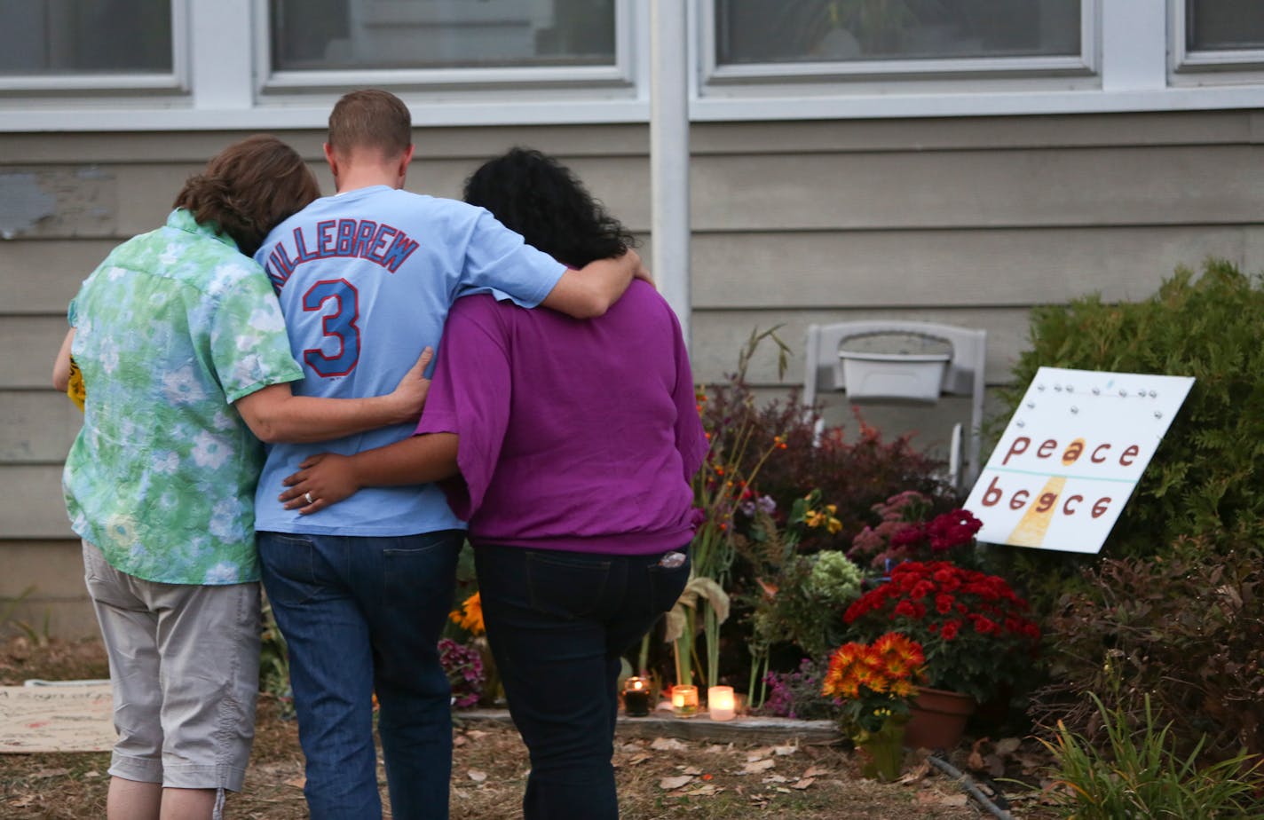 A family members of Ron Edberg consoled his son Dusty, center, in front of an informal memorial made for the victims in front of Accent Signage Systems in Minneapolis on Saturday Sept. 29, 2012. Ron Edberg was one of the employees that lost his life Thursday at the hands of Andrew Engeldinger.