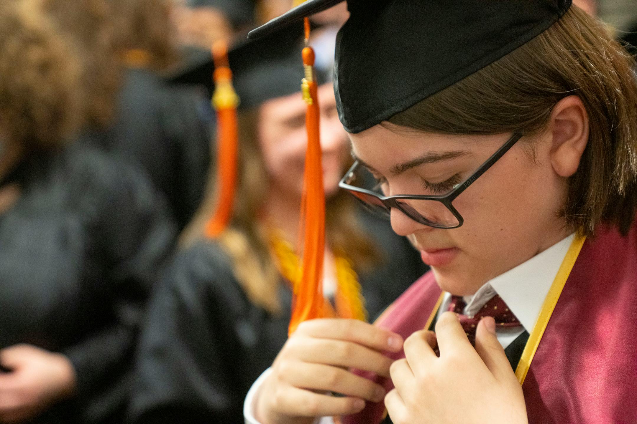 Elliott Tanner, 13, adjusts his tie while standing among his fellow physics department graduates in a holding area before his graduation.