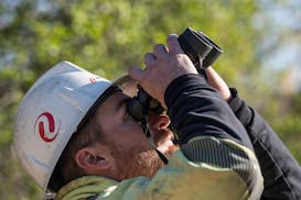 Lineman Bobby Weber uses some binoculars to inspect a high power line pole in Inver Grove Heights, Minn., on Wednesday, April 24, 2024. Utilities incl
