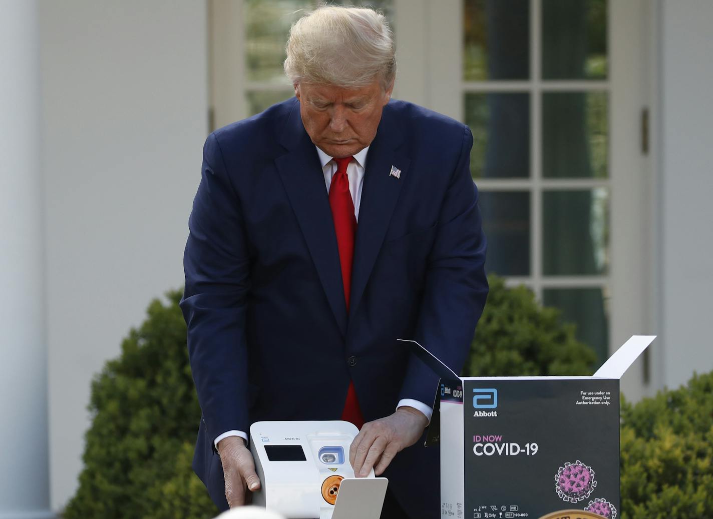 President Donald Trump opens a box containing a 5-minute test for COVID-19 from Abbott Laboratories as Stephen Hahn, commissioner of the U.S. Food and Drug Administration, speaks about the coronavirus in the Rose Garden of the White House, Monday, March 30, 2020, in Washington. (AP Photo/Alex Brandon) ORG XMIT: DCAB315