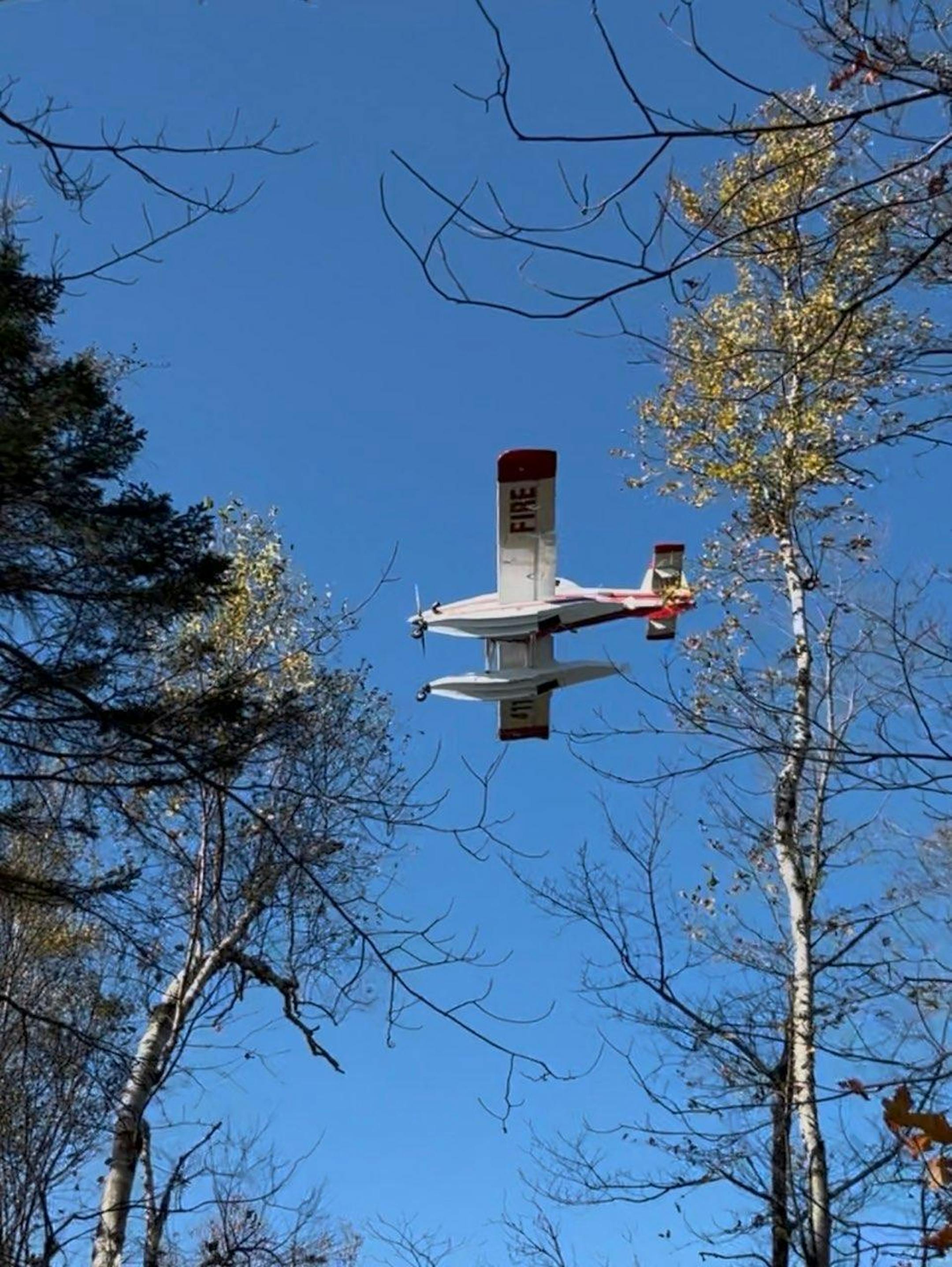 A water-scooping aircraft flies near the Crosby fire in North Shore.