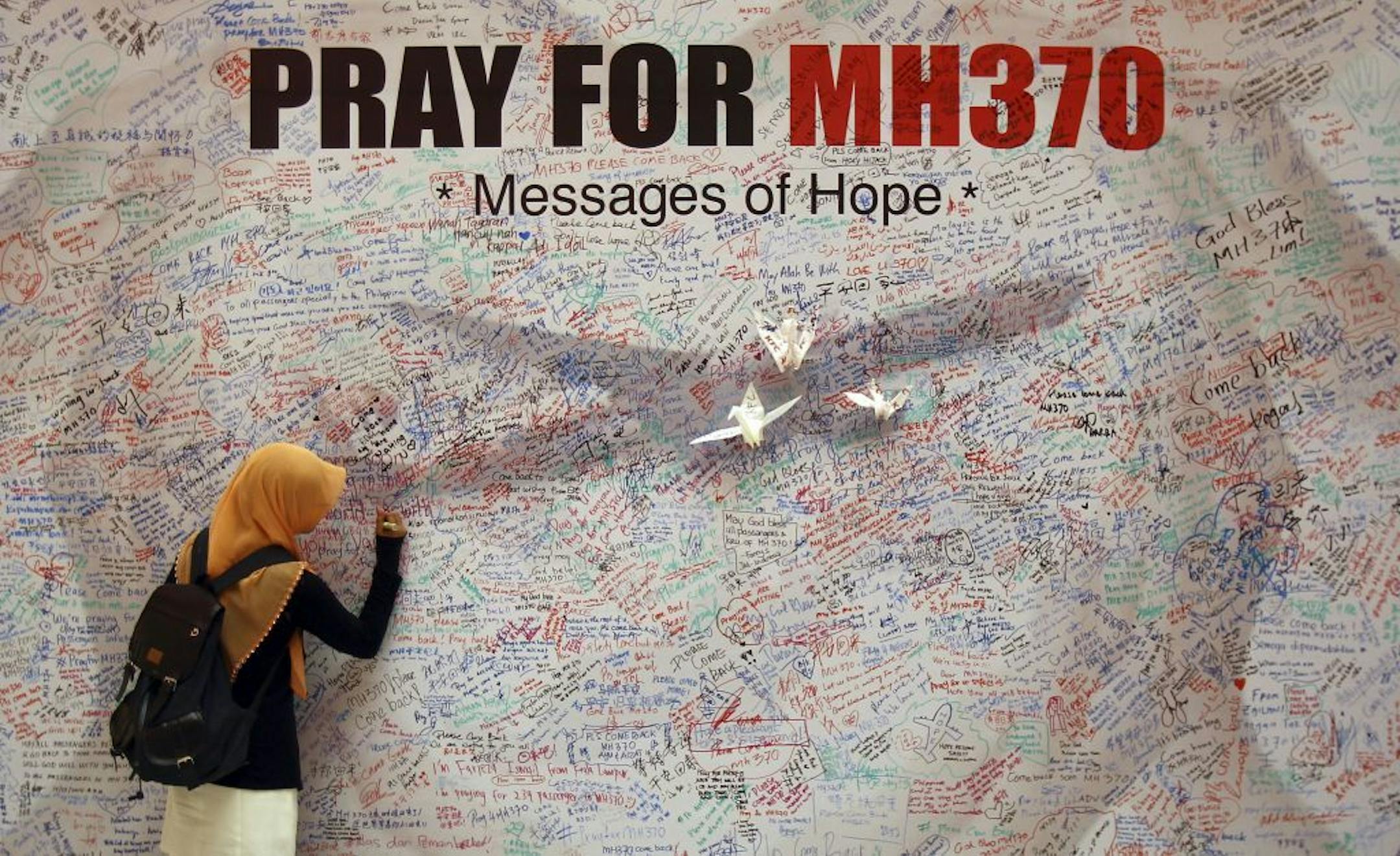 A woman writes a message for passengers aboard a missing Malaysia Airlines plane, at a shopping mall in Kuala Lumpur, Malaysia, Saturday, March 15, 2014. Investigators have concluded that one or more people with significant flying experience hijacked the missing Malaysia Airlines jet, switched off communication devices and steered it off-course, a Malaysian government official involved in the investigation said Saturday.