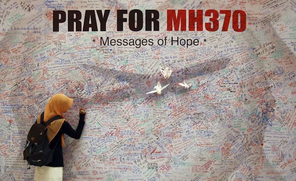 A woman writes a message for passengers aboard a missing Malaysia Airlines plane, at a shopping mall in Kuala Lumpur, Malaysia, Saturday, March 15, 20