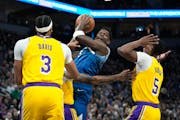 Minnesota Timberwolves guard Anthony Edwards, center, works toward the basket as Los Angeles Lakers forwards Anthony Davis (3) and Cam Reddish (5) def