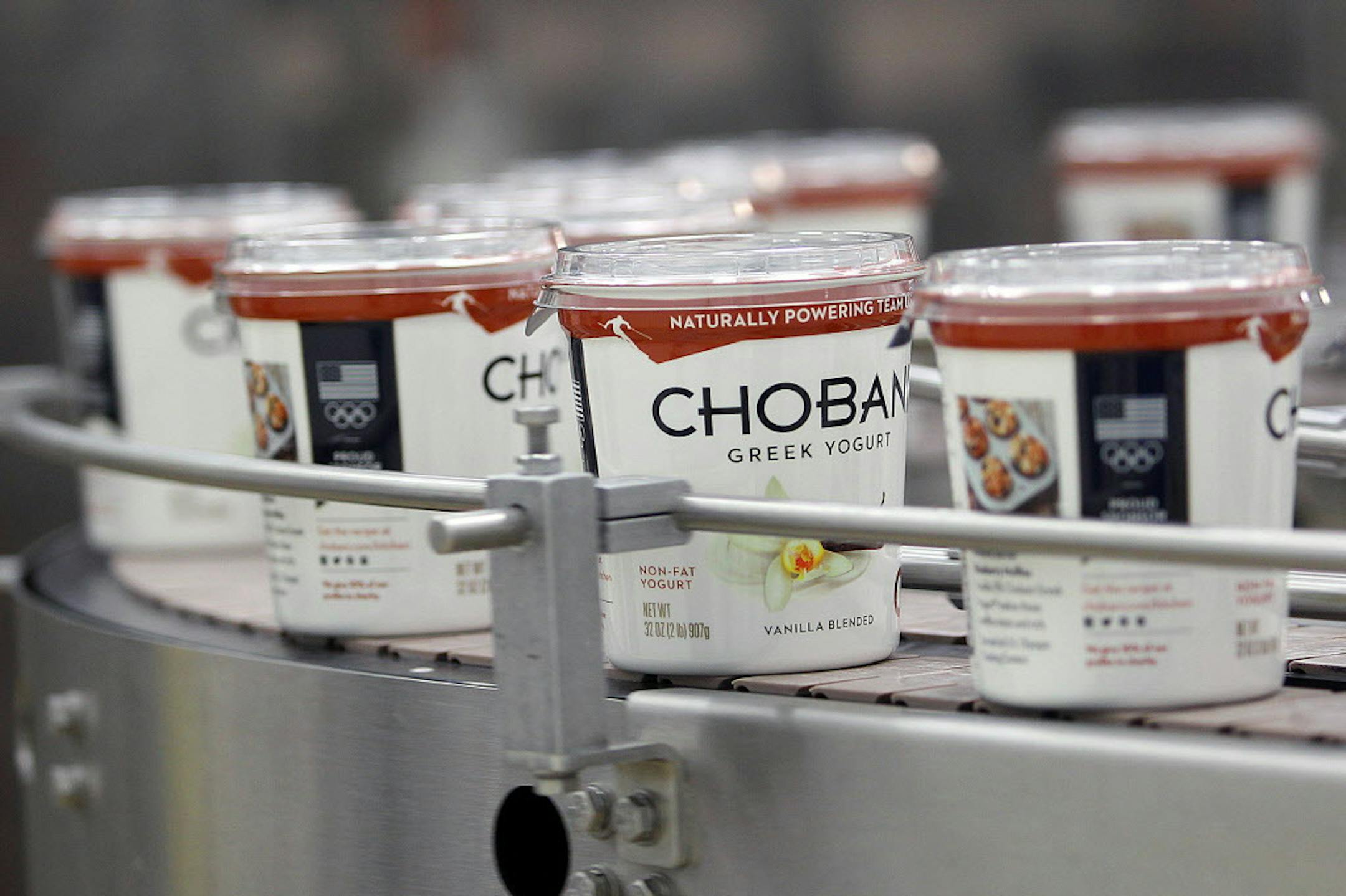 FILE - In this Jan. 21, 2014, file photo, yogurt containers run along a conveyer at the Chobani plant near Twin Falls, Idaho. Greek yogurt maker Chobani said it is giving its employees an ownership stake in the privately held company. The shares being distributed would amount to 10 percent of the companyís future value in the event of a sale or initial public offering. Chobani said each of its approximately 2,000 full-time employees will receive shares based on their role and time spent wit