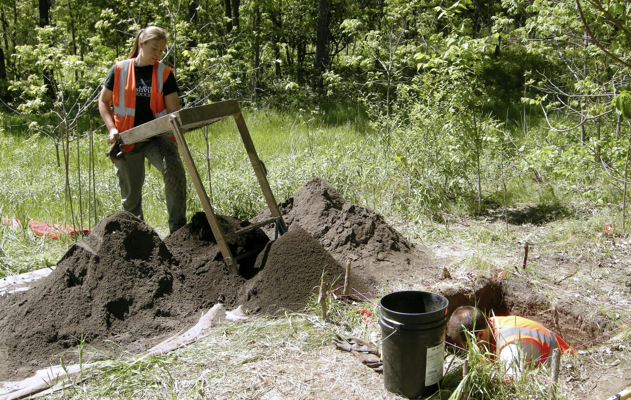 Crew members with the 106 Group working on the archaeological project in 2015, in preparation for road work on Flying Cloud Drive between Chanhassen and Eden Prairie. Cameo Kale is to the left screening excavated soil for artifacts, and Scott Tooker is in the excavation unit.