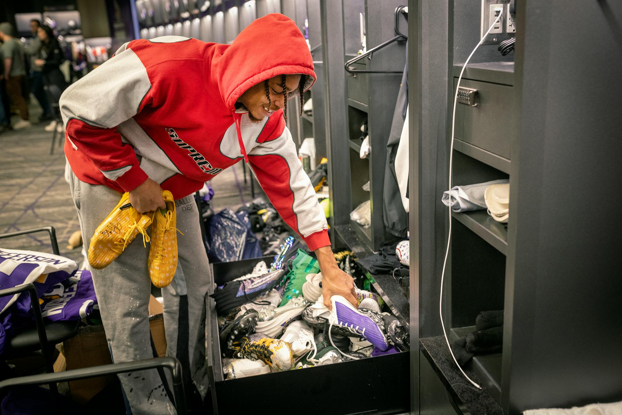 Minnesota Vikings wide receiver Justin Jefferson (18) gives out his cleats to other players in the locker room.