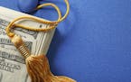 A stack of one hundred dollar bills on top of a blue graduation cap. A gold graduation tassel is draped over the stack of money. The ledft side of ima