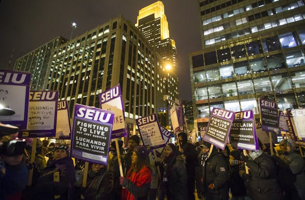 People walked holding signs in a circle during a one-day protest for local janitors a outside the U.S. Bank building on Wednesday, February 17, 2016, 