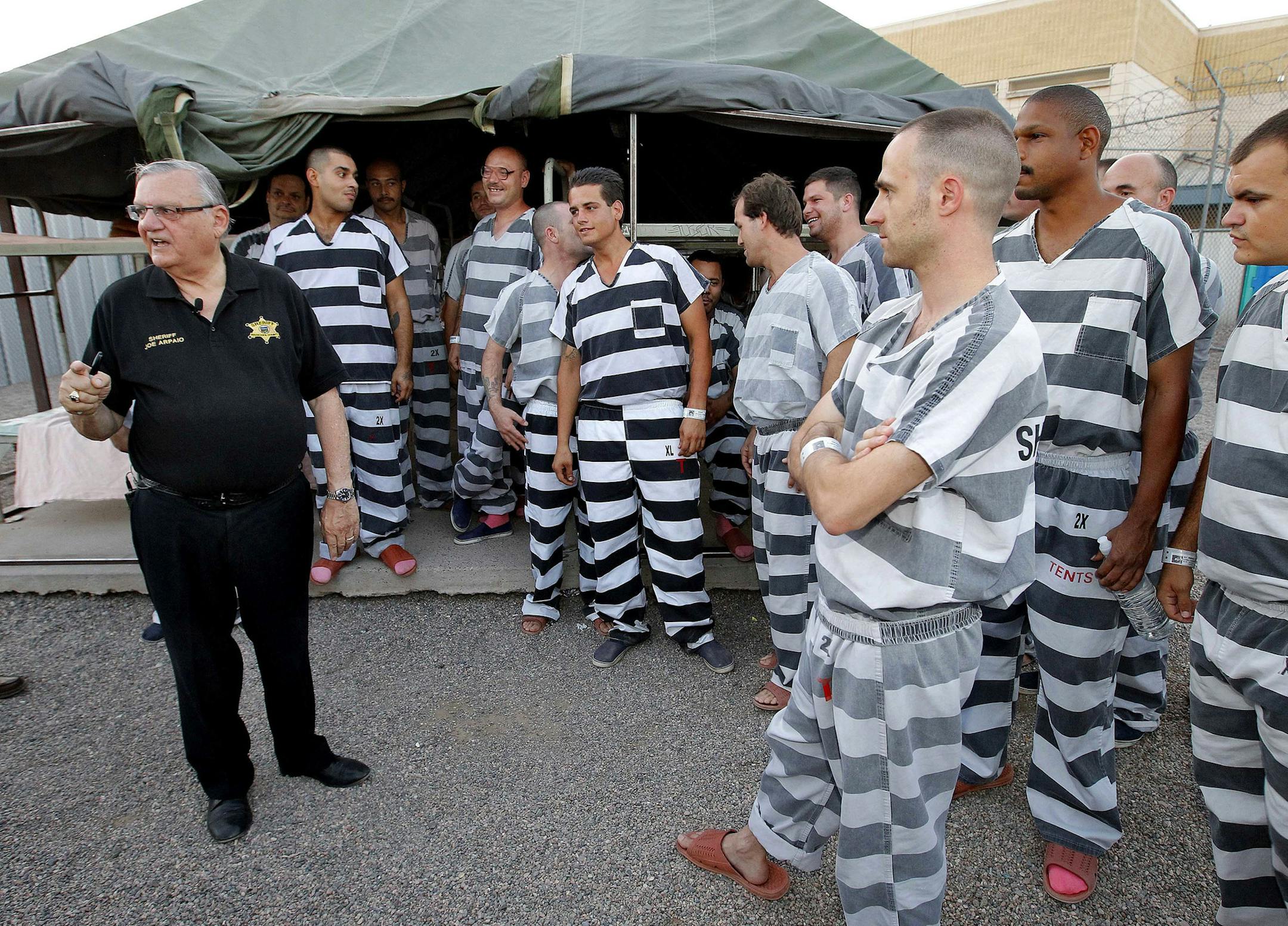 FILE - In this , June 23, 2012, file photo, inmates gather next to Maricopa County Sheriff Joe Arpaio as he walks through a Maricopa County Sheriff's Office jail called "Tent City" in Phoenix. Arpaio disbanded a SWAT team that focused on handling dangerous jail inmates at a time when the elite unit was in high demand due to a spike in assaults by inmates on guards, records show. Arpaio folded the Special Response Team in September as part of $8 million in budget cuts to cover skyrocketing legal