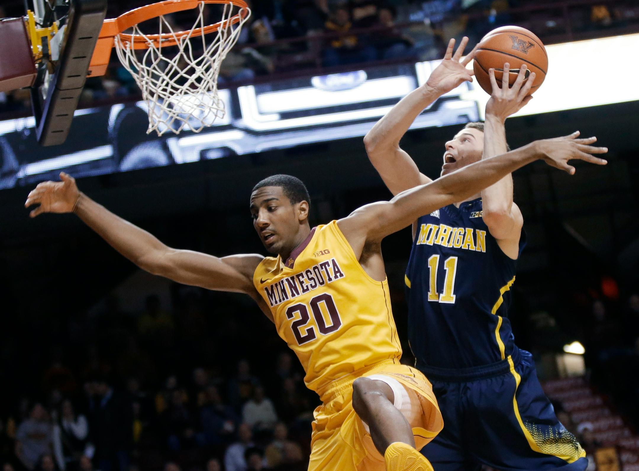 Michigan's Nik Stauskas, right, attempts a shot and is fouled by Minnesota's Austin Hollins during the first half of an NCAA college basketball game Thursday, Jan. 2, 2014, in Minneapolis. (AP Photo/Jim Mone)