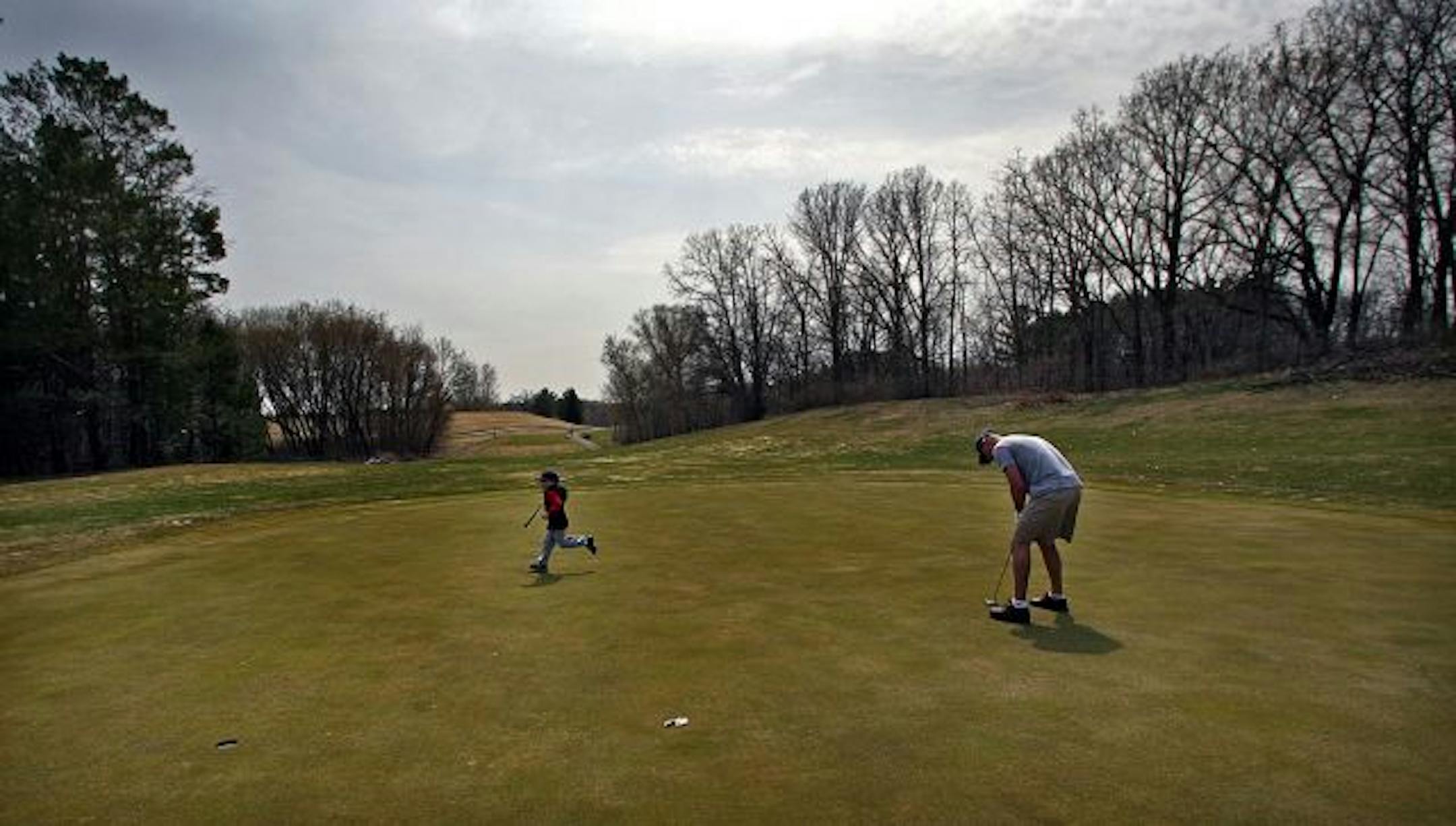 An enthusiastic five-year-old Jack Knoll ran to a golf cart after he finished putting on the fifth hole of the executive 9 hole golf course at at Inver Wood Golf Course in Inver Grove Heights. Jack's father, Karry, is putting at right.