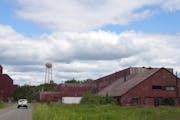 A truck drove past rusted and vacant buildings in July at the PolyMet processing site in Hoyt Lakes, Minn. 