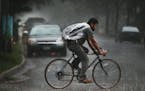 A bicyclist makes his way in the rain along Lyndale Avenue near Minnehaha Creek during a thunderstorm Tuesday, July 25, 2017, in south Minneapolis, MN
