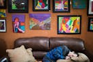 Jimmy Reagan sits on a couch below some of his artwork on display at Sunfish Cellars Wine & Spirits in St. Paul.