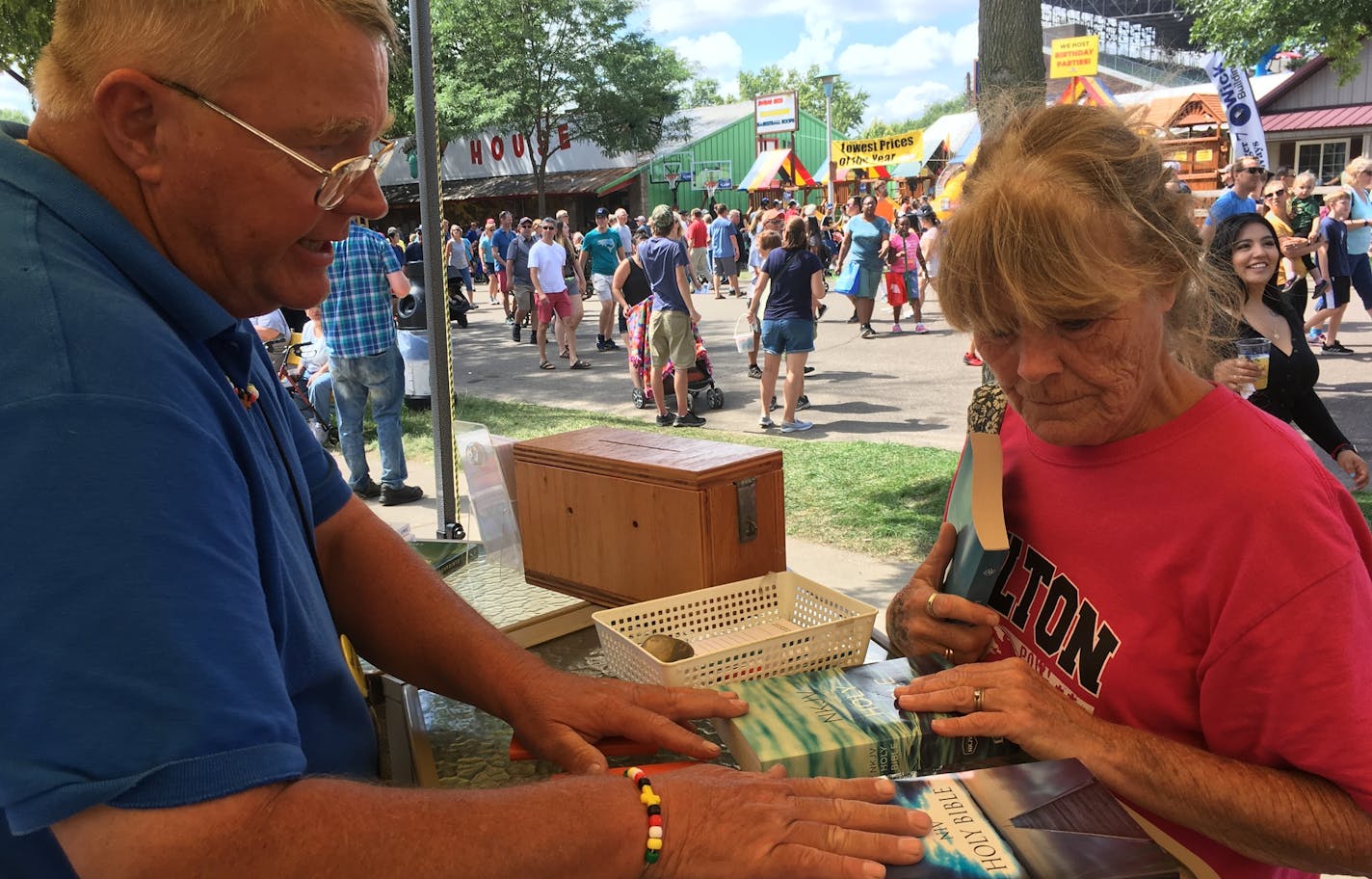 Dean Wiberg of Crossroads Chapel showed fairgoer Connie Grandy a selection of free Bibles available outside the longtime chapel at the State Fair.