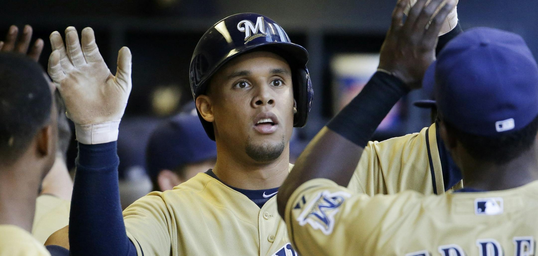 Milwaukee Brewers' Carlos Gomez is congratulated in the dugout after scoring a run during the first inning of a baseball game against the Chicago Cubs Friday, May 30, 2014, in Milwaukee. (AP Photo/Morry Gash) ORG XMIT: WIMG1