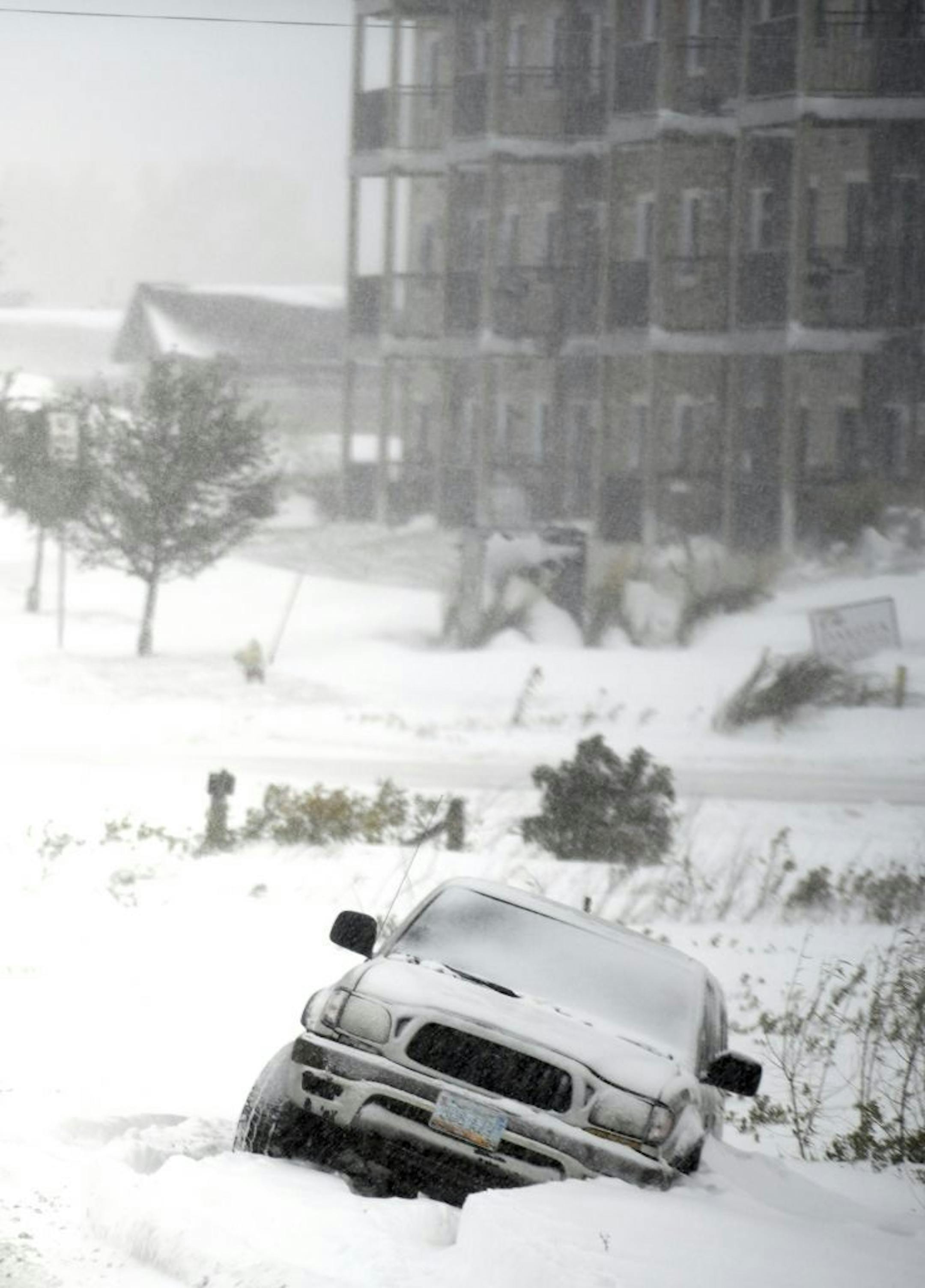 An abandoned SUV is stuck in a snow-filled ditch after the driver slipped off the road near the intersection of North 19th Street and 43rd Ave NE, Friday, Oct. 11, 2019 in Bismarck, N.D. North Dakota Gov. Doug Burgum on Friday activated the state's emergency plan due to what he called a crippling snowstorm that closed major highways and had farmers and ranchers bracing for the potential of huge crop and livestock losses.
