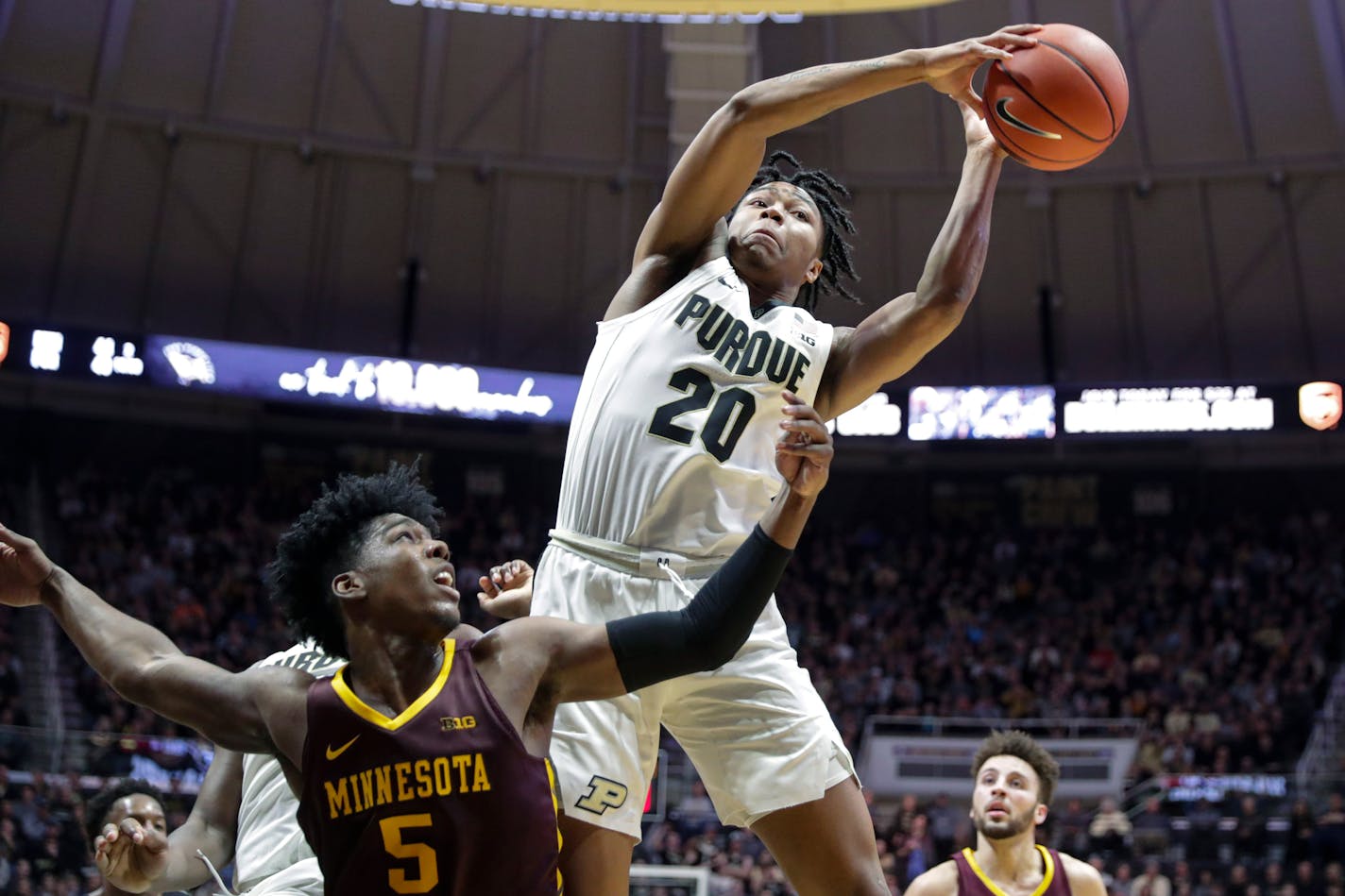 Purdue guard Nojel Eastern (20) grabs a rebound over Minnesota guard Marcus Carr (5) during the second half of an NCAA college basketball game in West Lafayette, Ind., Thursday, Jan. 2, 2020. Purdue won 83-78 in double overtime. (AP Photo/Michael Conroy)