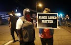 A woman holds up a sign which reads "Black Lives Matter" in Ferguson, Mo., on Monday, Aug. 10, 2015. A state of emergency was declared for Ferguson an