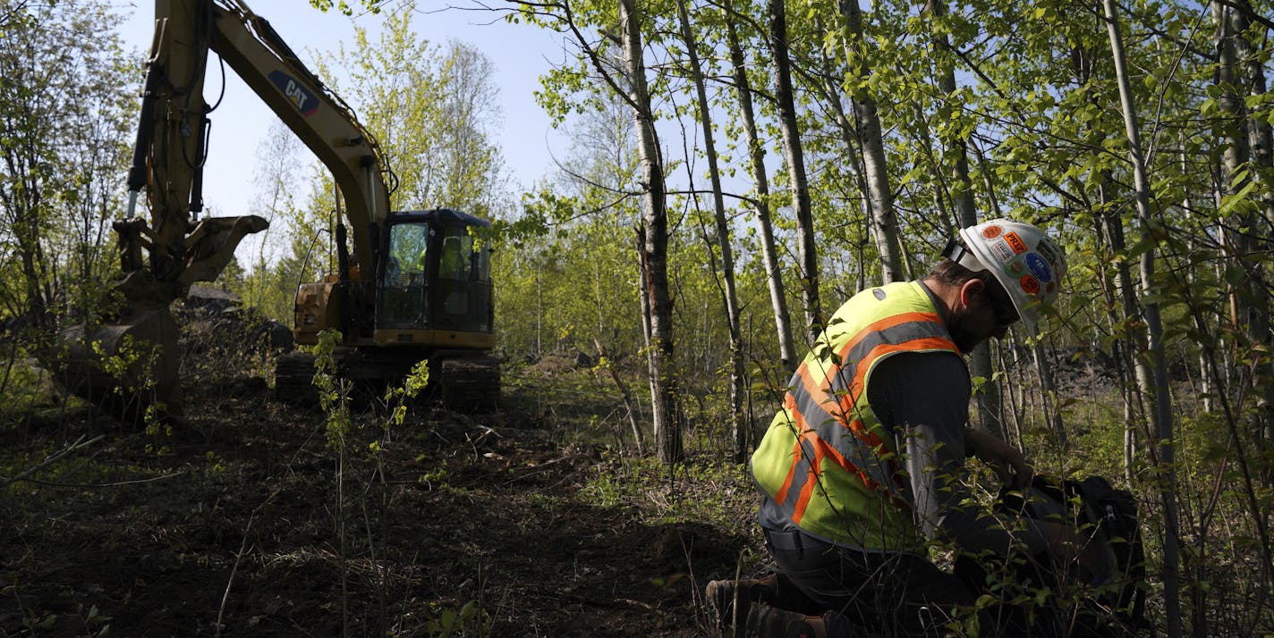 In this Wednesday, May 29, 2019, Eric Olson, right, gathers his tools as contractor Robert Radotich uses a backhoe to dig areas so the soil stratification can be observed which will help them engineer and design the infiltration pods for the Polymet copper-nickel mine in Hoyt Lakes, Minn. The developers of the proposed mine in northern Minnesota are courting bankers for nearly $1 billion to move ahead with the project, even as opponents hold out hope of blocking the operation due to fears of wat