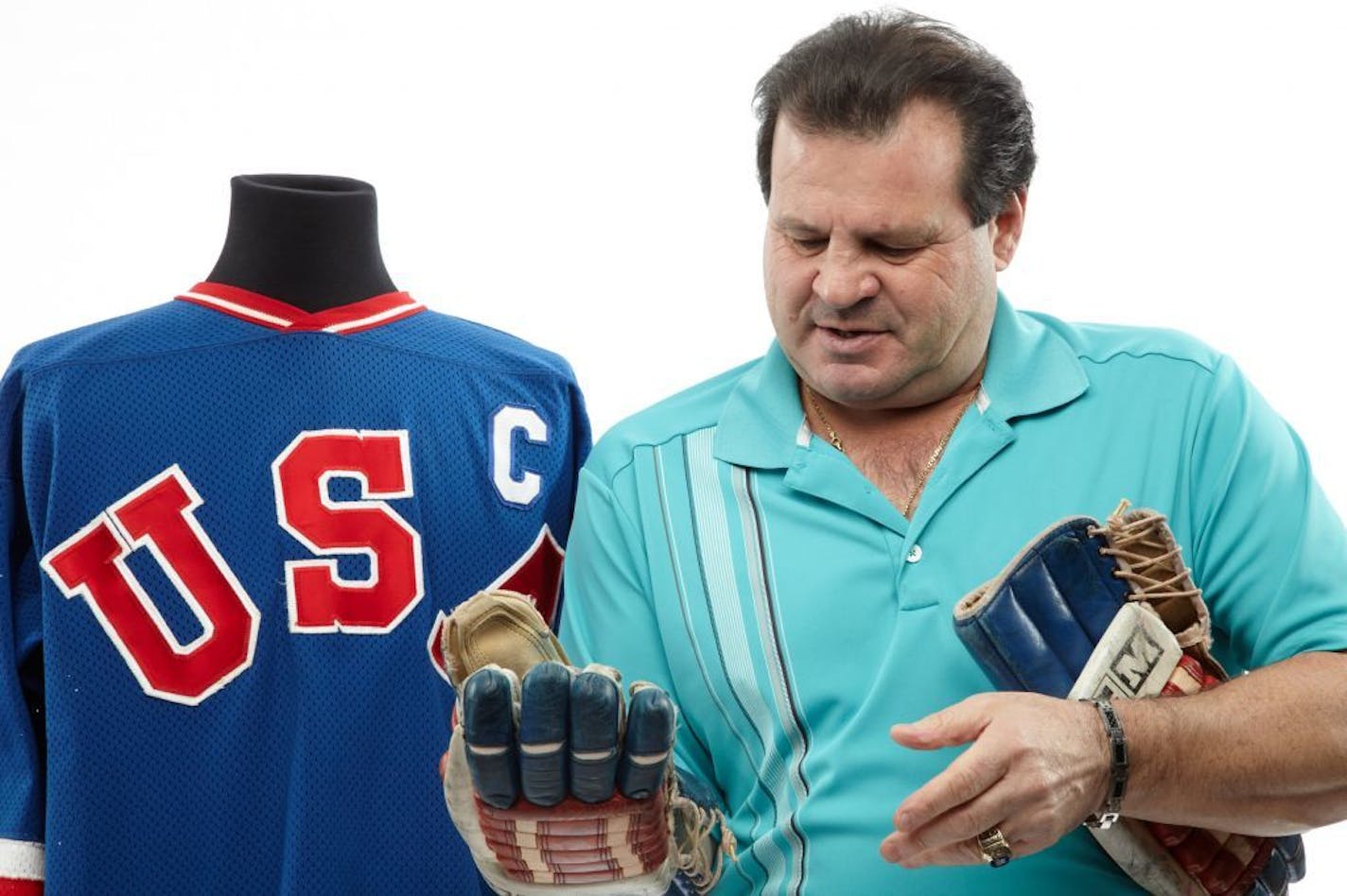 This Dec. 12, 2012 handout photo, provided by Heritage Auctions, shows former United States Olympic hockey player Michael Eruzione in Dallas with a jersey and the and gloves from his team's win against the Soviet Union hockey team at the 1980 Winter Olympics. The �Miracle On Ice� paraphernalia will be offered by Dallas-based Heritage Auctions in New York on Feb. 22, the 33rd anniversary of that historic game.