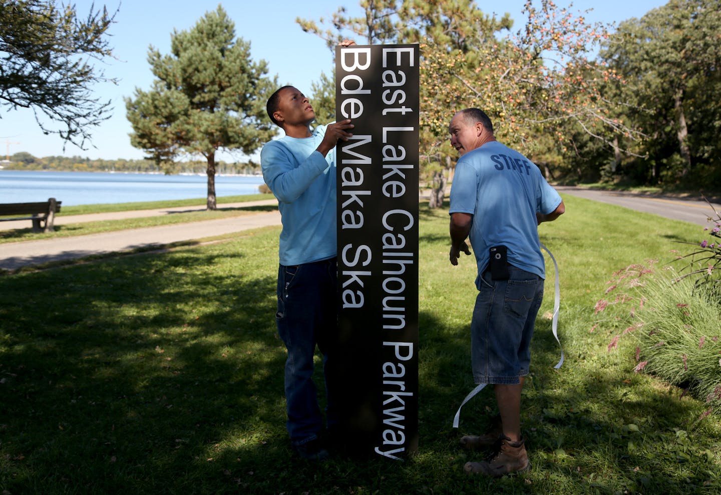 Minneapolis Park and Recreation employees Dan Falk, left, and Tim Coffin prepared one of several new signs installed Friday around Lake Calhoun in Minneapolis with the lake&#x2019;s Dakota name, Bde Maka Ska.