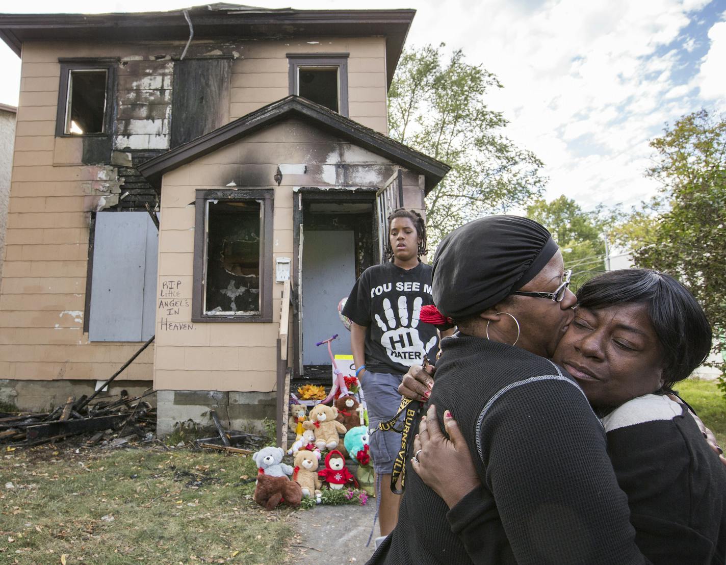 Charlotte Fikes, left, the great aunt of three children who perished in a fire the night before, is consoled by another family member Karen Carter, right, in front of the Penn Avenue home that burned in Minneapolis on Sunday, October 4, 2015. ] LEILA NAVIDI leila.navidi@startribune.com / BACKGROUND INFORMATION: Three young children died in a late-night fire October 3, 2015 in a house in north Minneapolis&#x2019; Jordan neighborhood that was without heat, the property owner said. One of the home&