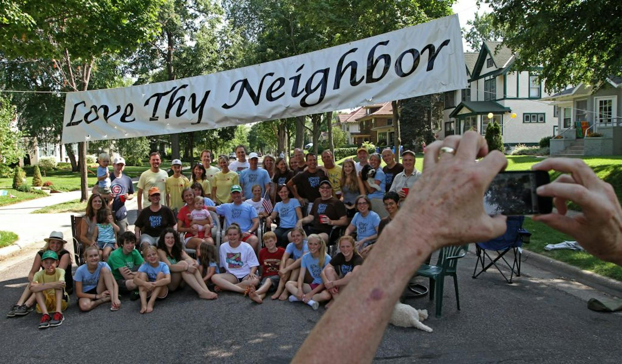Residents and alumni of the 5000 block of Aldrich Ave. South in Minneapolis, gathered for a group photo under the blocks "Love Thy Neighbor" banner that has gone up every year for the block party. This year's Aldrich block party was held on 7/28/12 and featured a rematch of a challenge made 40 years ago to the 5100 block of Aldrich to a volleyball match. The 5000 block of Aldrich won the volleyball rematch that was held on the block. The 5000 Aldrich Ave. South held it's first block party in 196