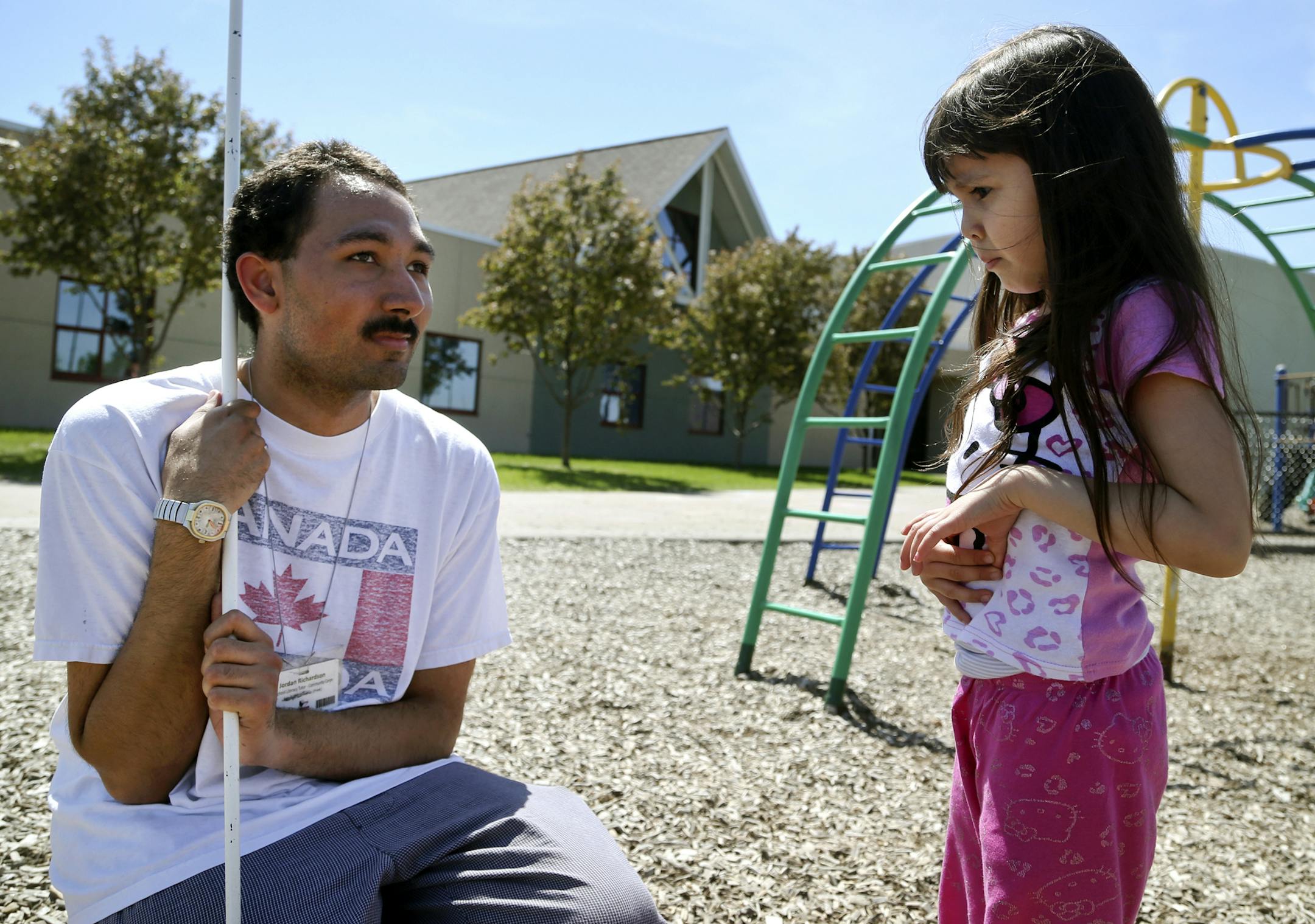 He’s just a big kid: Jordan Richardson talks to Earle Brown Elementary pre-Kindergarten student Bella Valencia on the playground. To Bella and her classmates, Richardson was just a big kid who sat with them in miniature chairs, read to and played games with them. Above, Richardson watches as children walk to their family members following pre-K graduation on Monday.