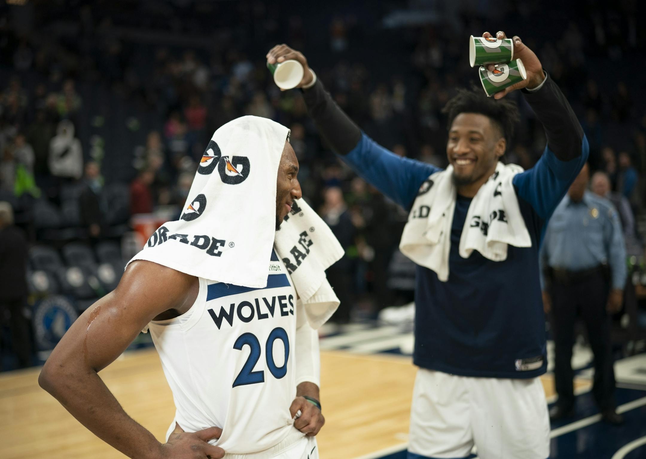 Josh Okogie looks back at his Timberwolves teammate Robert Covington after receiving a mini-Gatorade shower from him while he was being interviewed by Fox Sports North's Marney Gellner after the game.