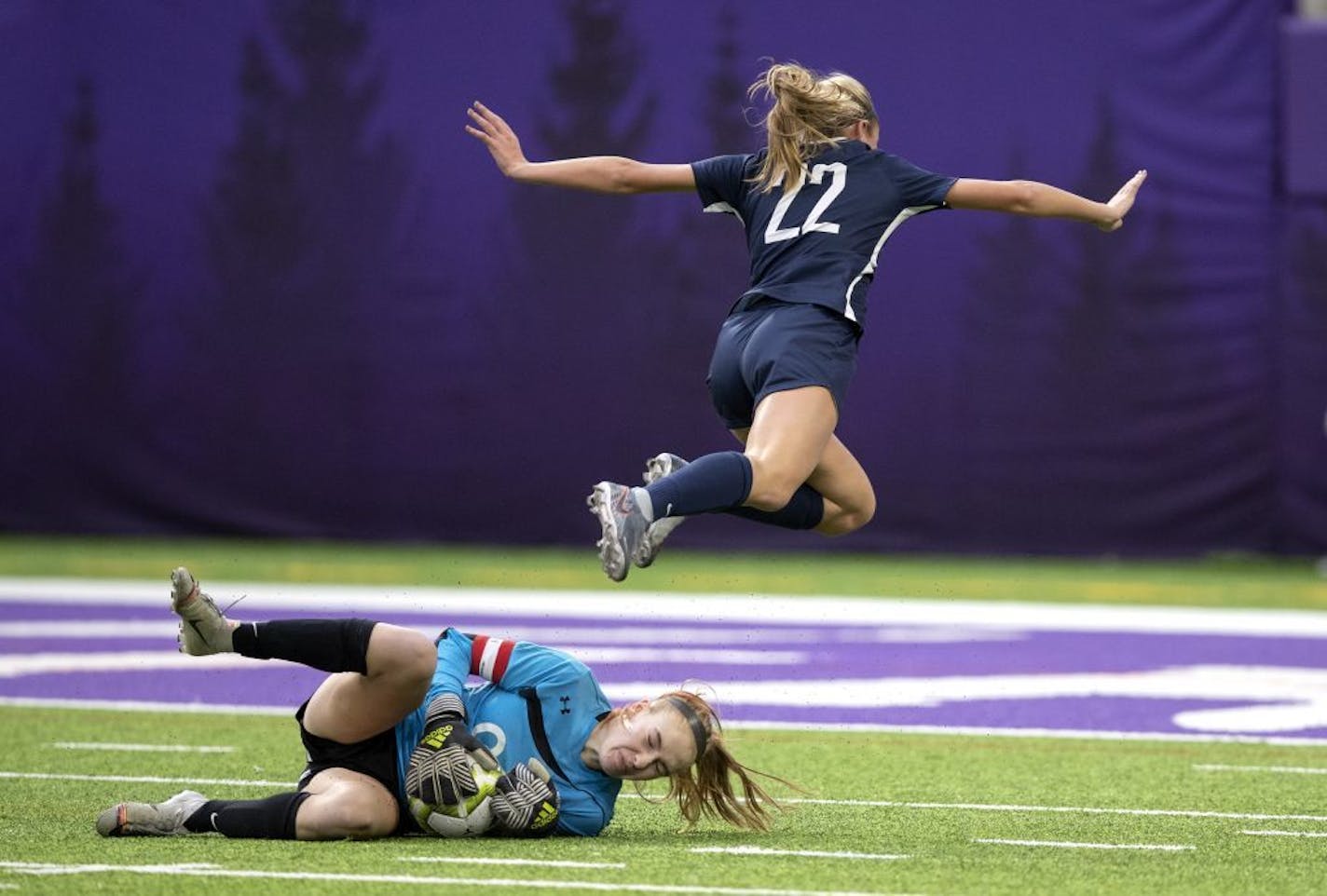 Orono goal keeper Clare Gagne made a save in the first half as Anna Wagner of Mahtomedi jumped over her .