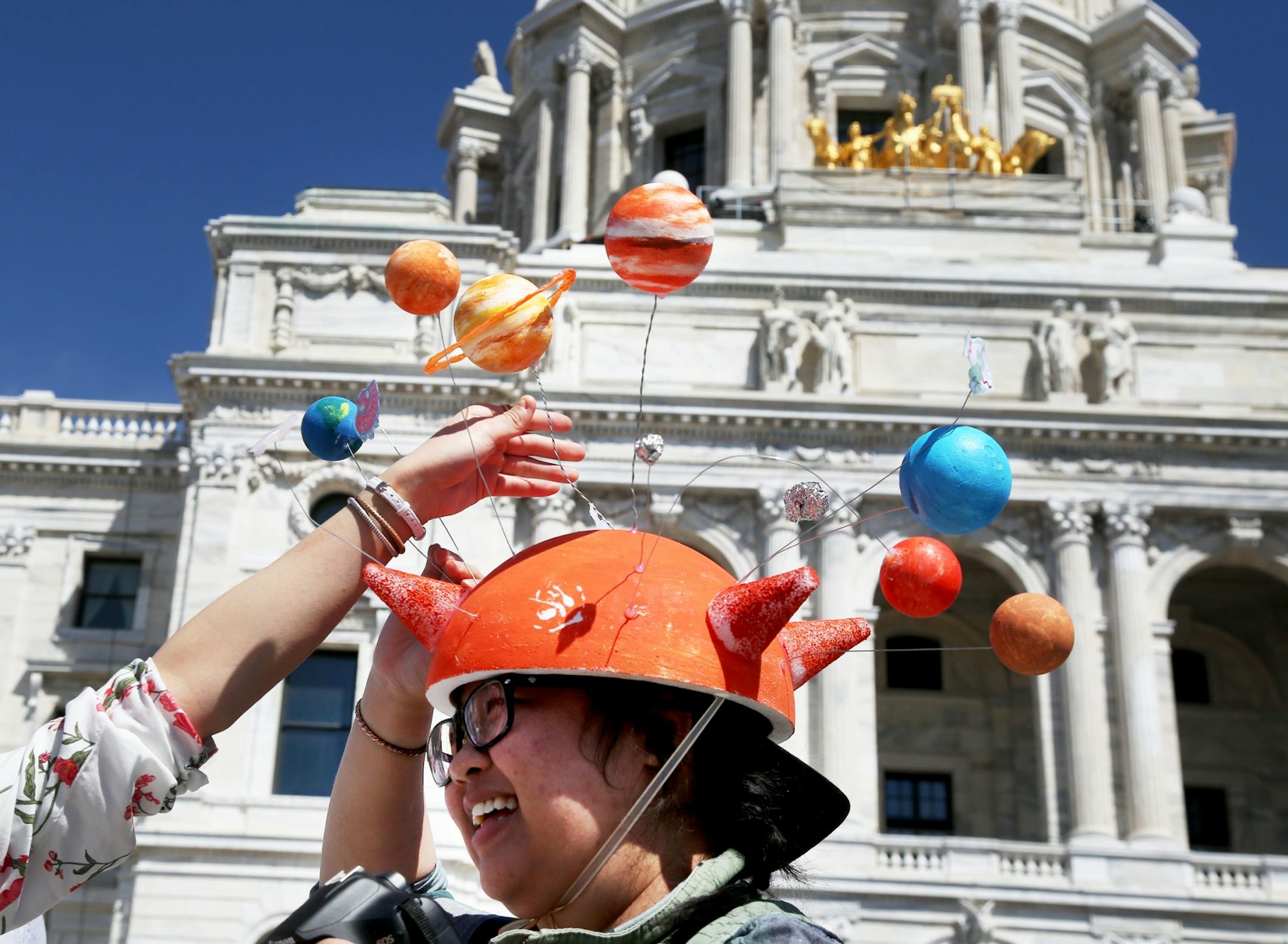 Tourmaline Vang, who works at a St. Paul women's clinic, got some help adjusting her solar system hat as she joined thousands of science supporters at the State Capitol.
