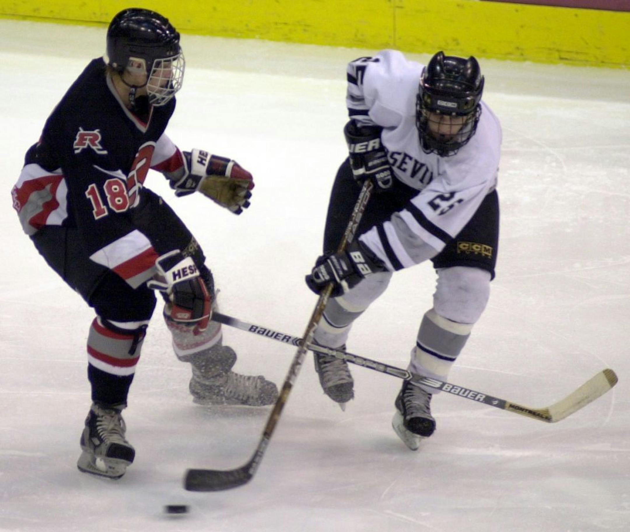 Elk River's Dominic Morris (left) battles for the puck with Roseville's Neil Schneider during a Christmas tournament game in 2001.