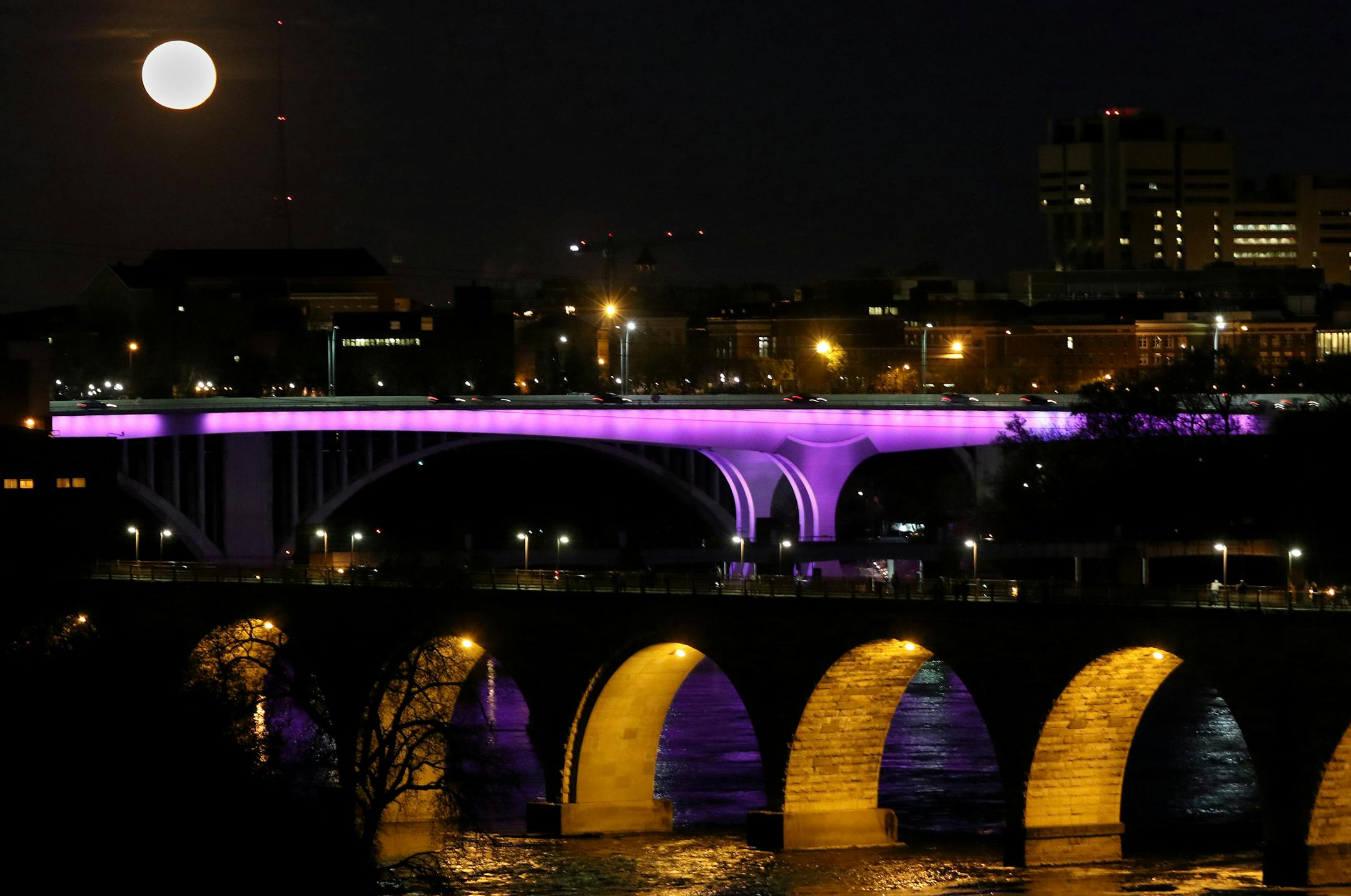 A full moon rises over the I-35-W bridge, which was lit up purple in April 2017, on the anniversary of the 2016 death of Minneapolis music icon Prince.