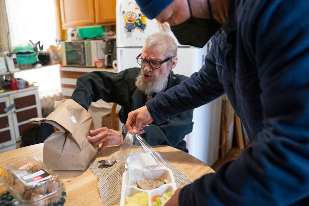Pete Magnuson opened a hot meal for Bruce Anderson in his home as part of the TRUST Meals on Wheels program Thursday in Minneapolis.